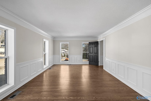 empty room featuring crown molding, visible vents, dark wood finished floors, and a textured ceiling