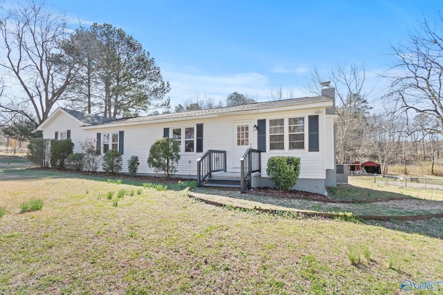 ranch-style home featuring a chimney, a front yard, and fence