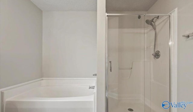 bathroom featuring shower with separate bathtub and a textured ceiling