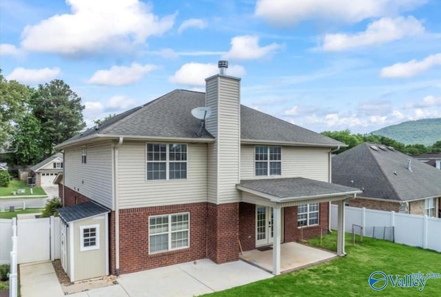 rear view of property with a mountain view, a patio, and a lawn