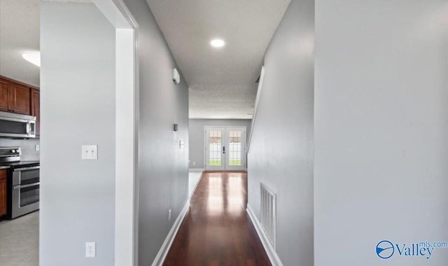 corridor with french doors and hardwood / wood-style floors