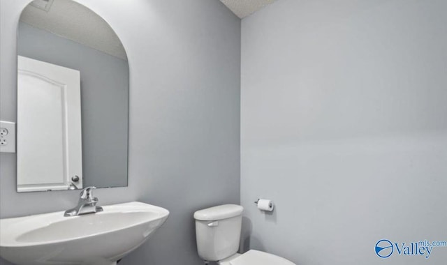 bathroom with sink, a textured ceiling, and toilet