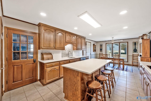 kitchen featuring a breakfast bar, brown cabinetry, a kitchen island, and light countertops