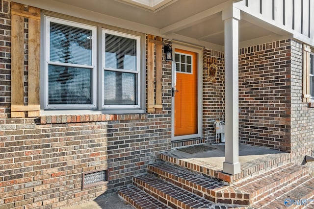 property entrance with board and batten siding and brick siding