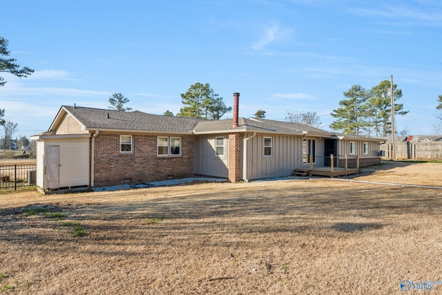 rear view of house with crawl space, a yard, fence, and brick siding