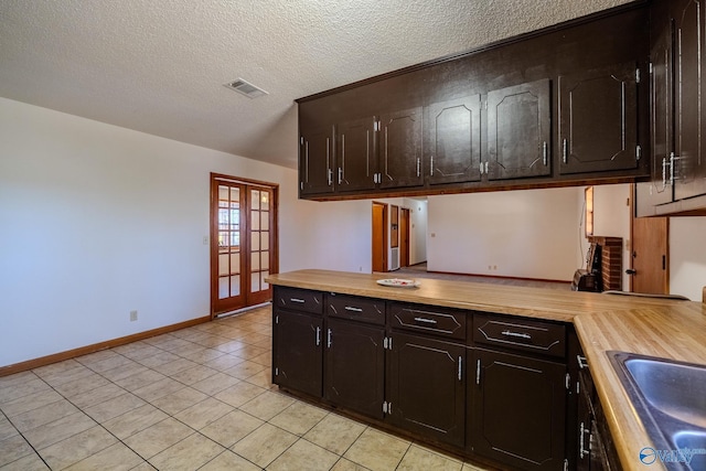 kitchen featuring visible vents, baseboards, light countertops, french doors, and a textured ceiling