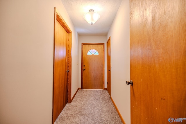 entryway with baseboards, carpet floors, and a textured ceiling