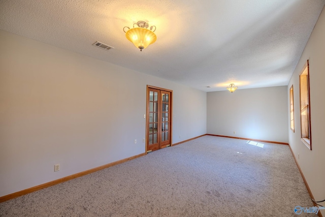 carpeted empty room featuring visible vents, a textured ceiling, and baseboards