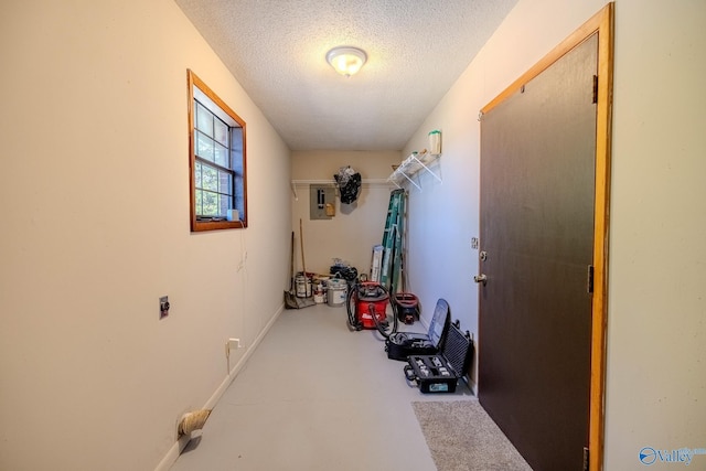 hall with baseboards, concrete floors, and a textured ceiling