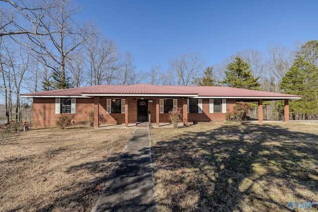 single story home featuring metal roof, a front yard, a carport, and brick siding