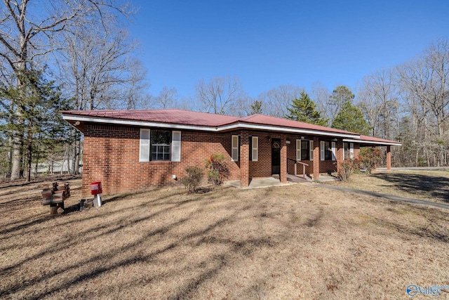 ranch-style house with metal roof, brick siding, a porch, and a front yard