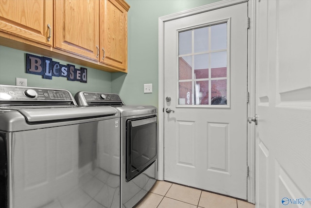 laundry room with washer and dryer, light tile patterned floors, and cabinets