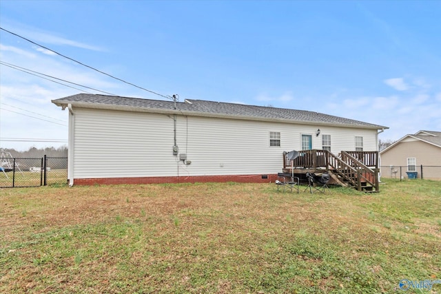 rear view of house with a wooden deck and a lawn