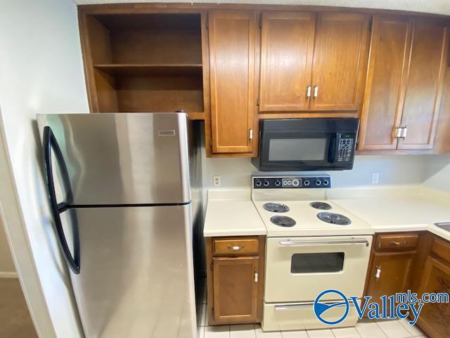 kitchen featuring stainless steel refrigerator, white range with electric stovetop, and light tile patterned flooring