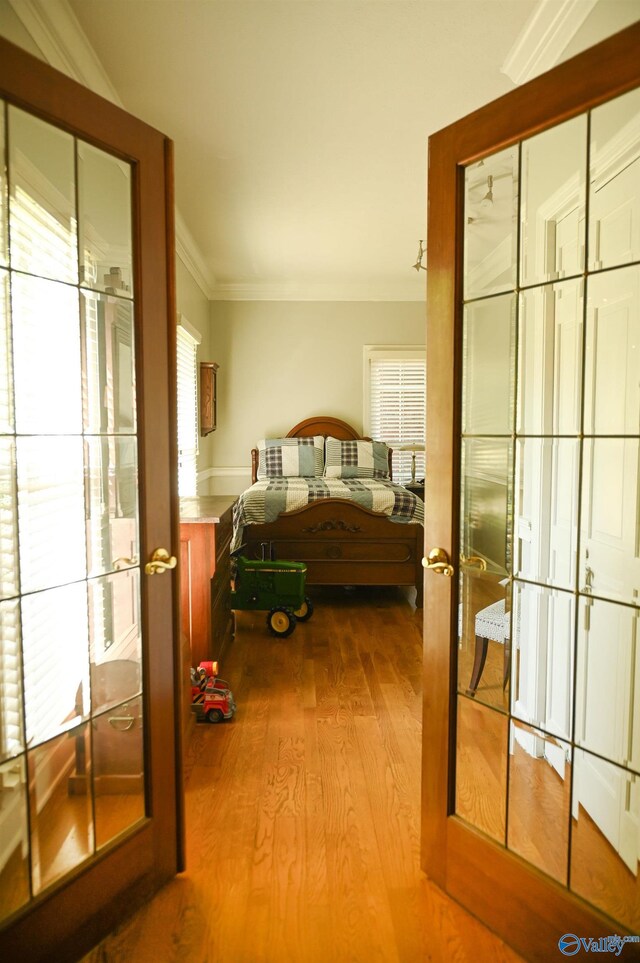 bedroom featuring french doors, ornamental molding, and hardwood / wood-style floors