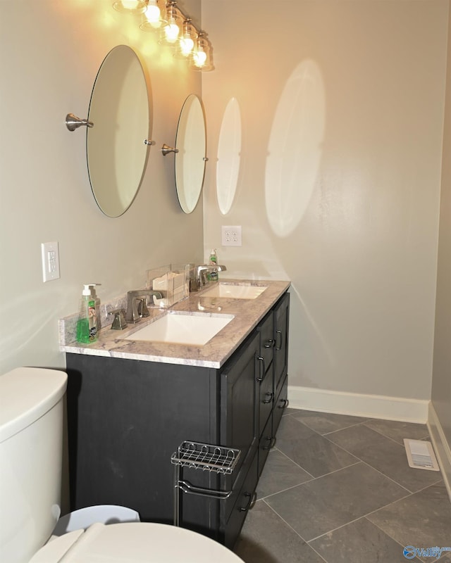 bathroom with double vanity, tile patterned flooring, and toilet