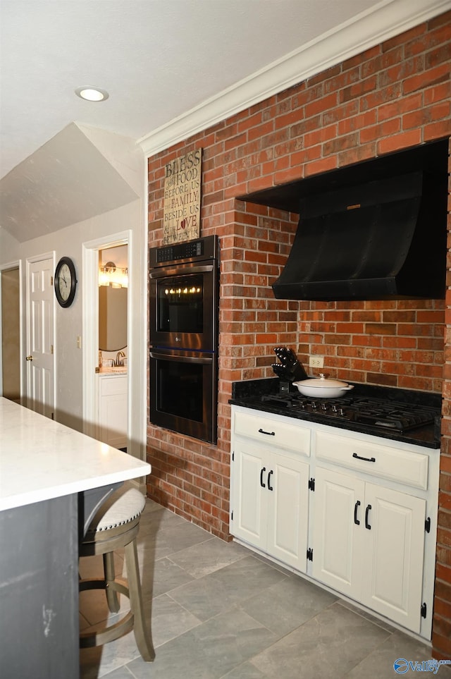 kitchen with black double oven, white cabinetry, exhaust hood, and light tile patterned floors