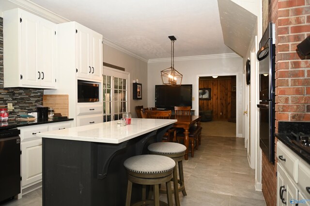 kitchen with hanging light fixtures, white cabinetry, a center island, and decorative backsplash