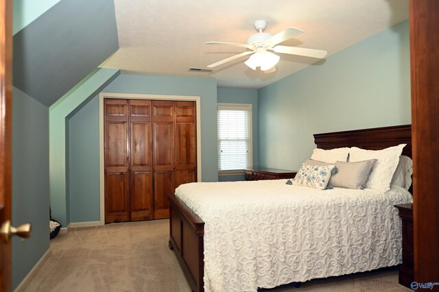 bedroom with ceiling fan, lofted ceiling, light carpet, and a closet