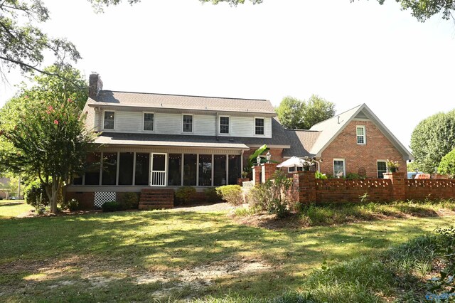 back of property with a lawn and a sunroom