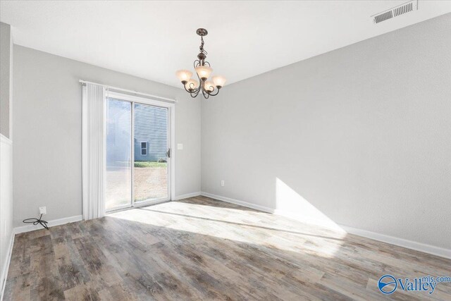 unfurnished room featuring wood-type flooring and a notable chandelier