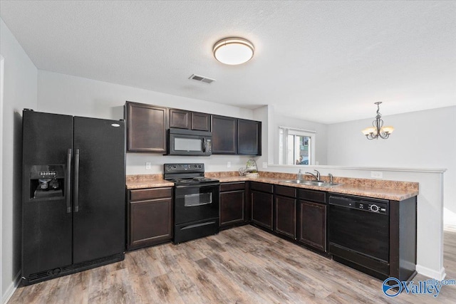 kitchen featuring dark brown cabinetry, sink, black appliances, pendant lighting, and light hardwood / wood-style flooring