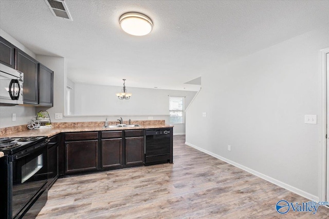 kitchen with a textured ceiling, sink, black appliances, light hardwood / wood-style flooring, and hanging light fixtures