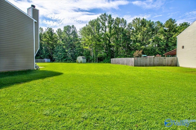 view of yard with a storage unit, fence, and an outdoor structure