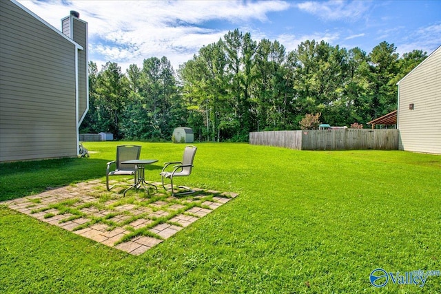 view of yard with a storage unit, fence, an outbuilding, and a patio area