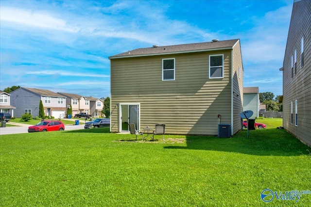 rear view of house featuring a residential view, a yard, and central AC unit
