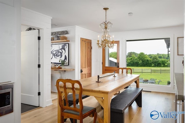 dining area with an inviting chandelier and light hardwood / wood-style flooring