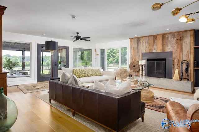 living room with ceiling fan, a high end fireplace, and light hardwood / wood-style floors