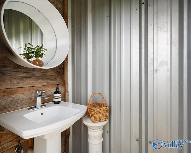 bathroom featuring wooden walls and sink