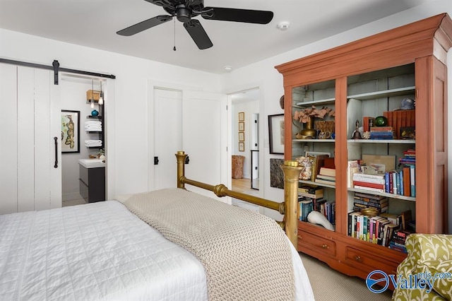 bedroom with a barn door, ceiling fan, and carpet flooring