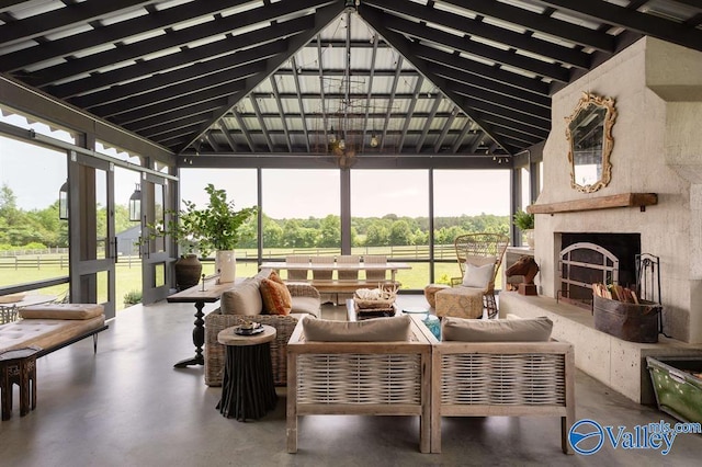 sunroom with an outdoor fireplace and lofted ceiling