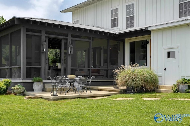 rear view of property featuring a lawn, a sunroom, and a patio