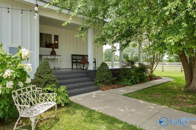 entrance to property featuring a lawn and covered porch