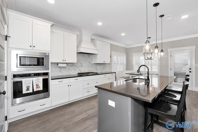 kitchen featuring premium range hood, crown molding, stainless steel appliances, and a sink