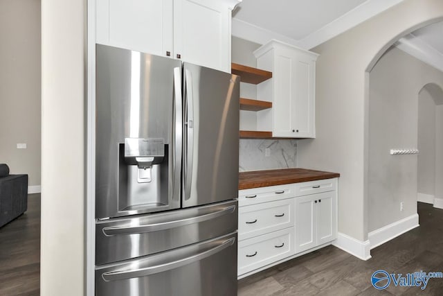 kitchen with arched walkways, butcher block countertops, stainless steel refrigerator with ice dispenser, decorative backsplash, and open shelves