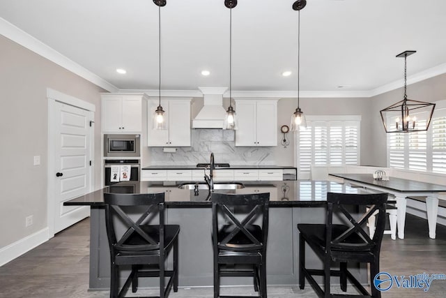 kitchen featuring appliances with stainless steel finishes, custom range hood, a sink, and crown molding