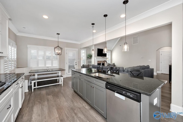 kitchen with arched walkways, visible vents, open floor plan, stainless steel dishwasher, and a sink