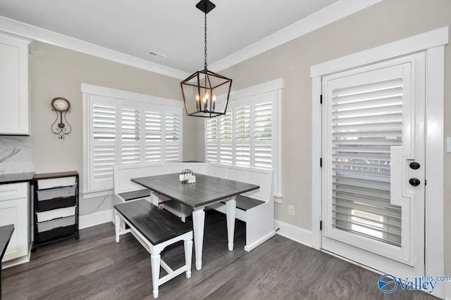 dining area featuring dark wood-style flooring, a notable chandelier, visible vents, ornamental molding, and baseboards