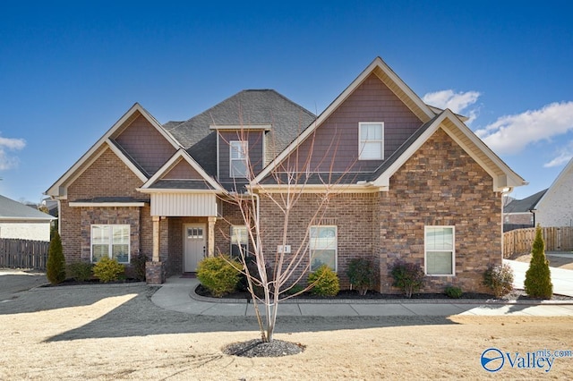 craftsman-style home with stone siding, fence, and brick siding