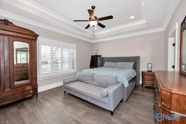 bedroom with ornamental molding, a raised ceiling, baseboards, and wood finished floors