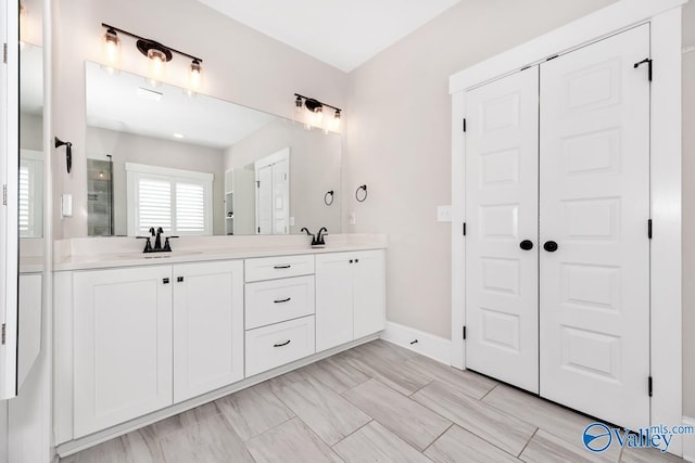 bathroom featuring double vanity, baseboards, and a sink