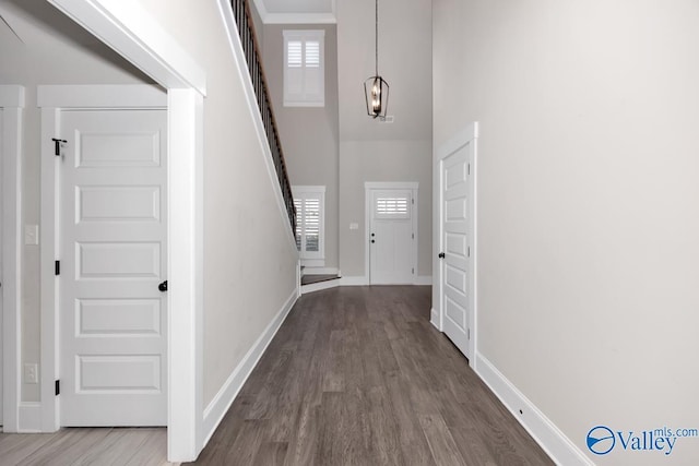 foyer with a wealth of natural light, stairway, baseboards, and wood finished floors