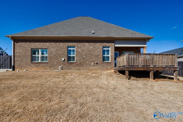 back of house with a shingled roof, a deck, and brick siding