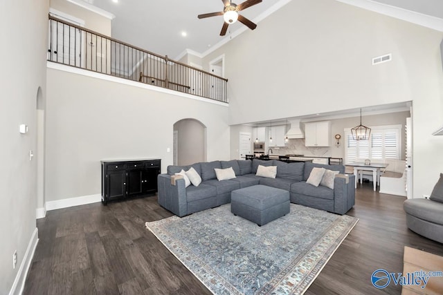 living room with arched walkways, dark wood-style floors, visible vents, and baseboards