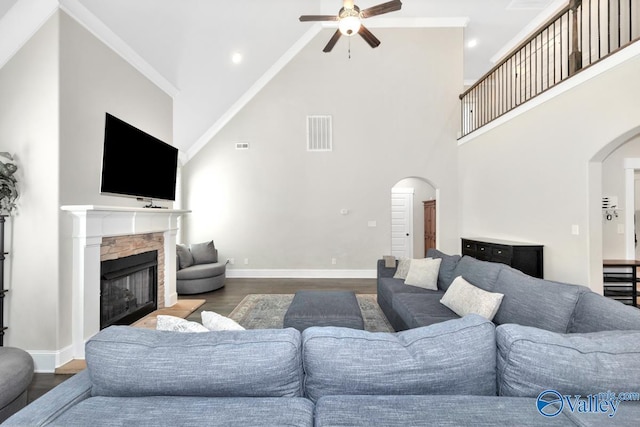 living room featuring baseboards, a fireplace, arched walkways, and wood finished floors