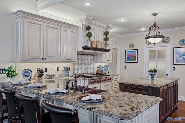 kitchen featuring light stone counters, a peninsula, ornamental molding, decorative backsplash, and dark wood finished floors